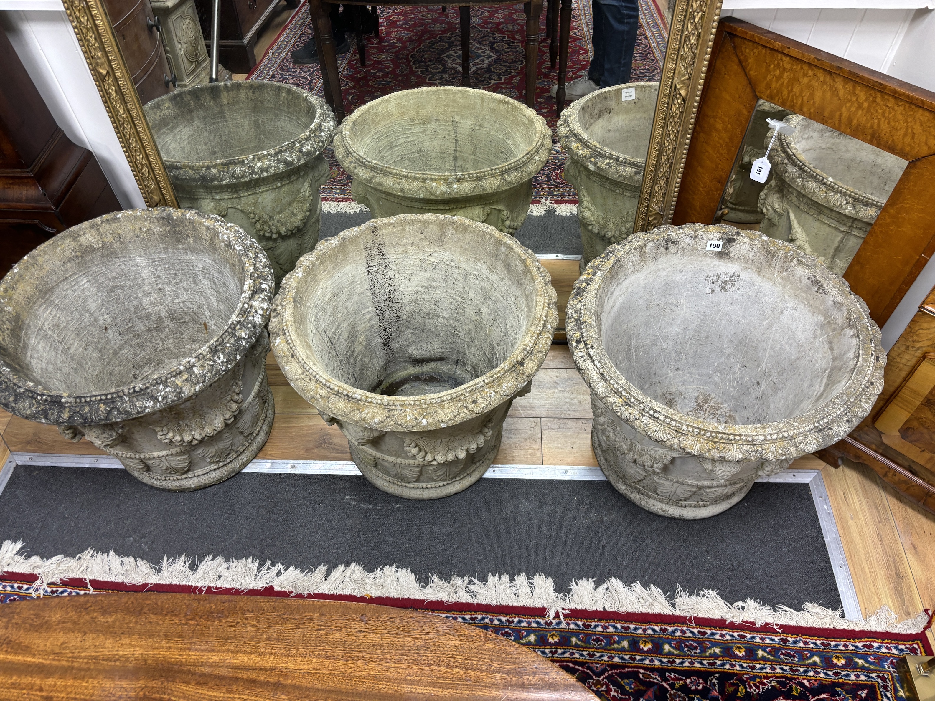 A set of three circular reconstituted stone garden urns with female mask swagged bodies, diameter 59cm, height 50cm